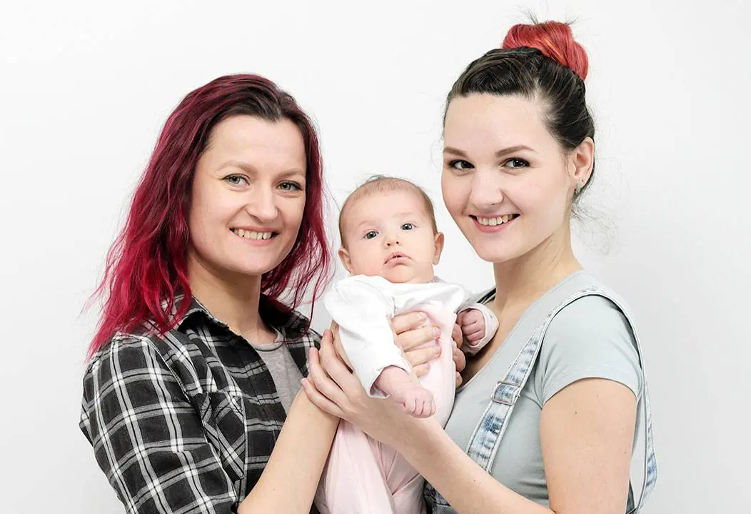 Two mothers holding their newborn baby