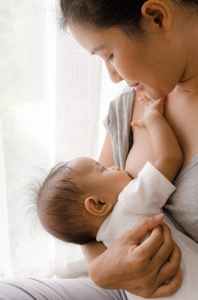 mother breastfeeding by window