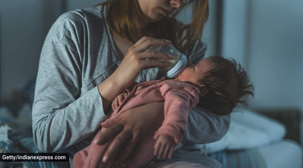 A parent feeding their baby in a dim room at night.