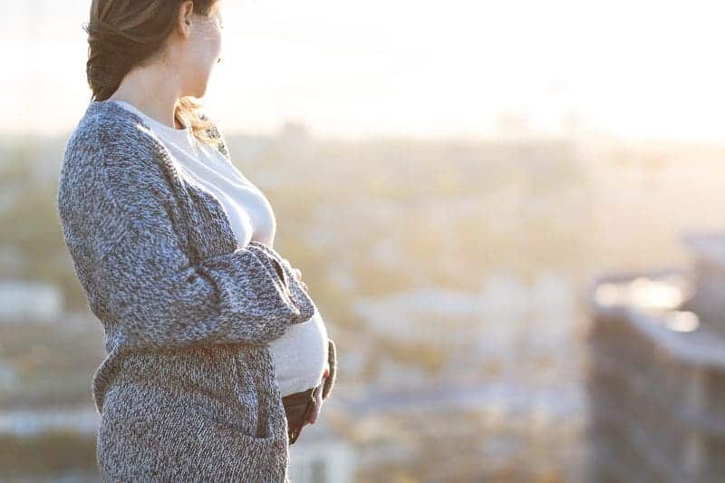 A happy pregnant woman outdoors on an autumn day.