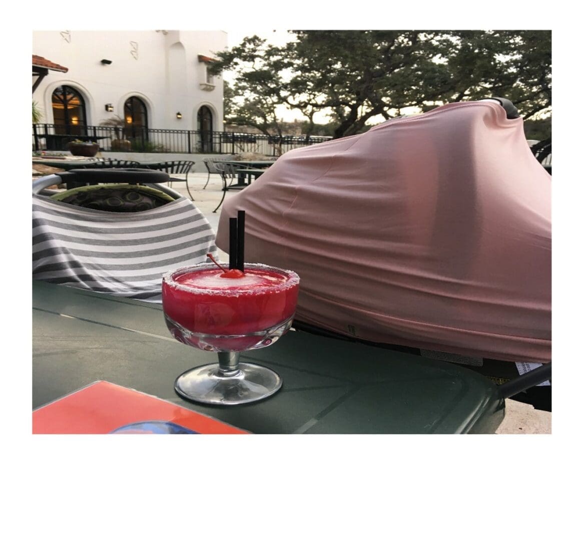 Margaritas on a patio table next to parked strollers during a moms' outing.