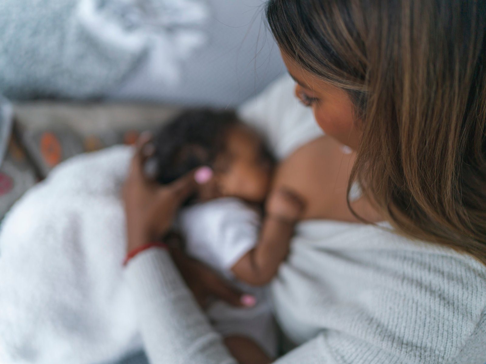 A parent holding a sleeping newborn close against the chest during a feeding