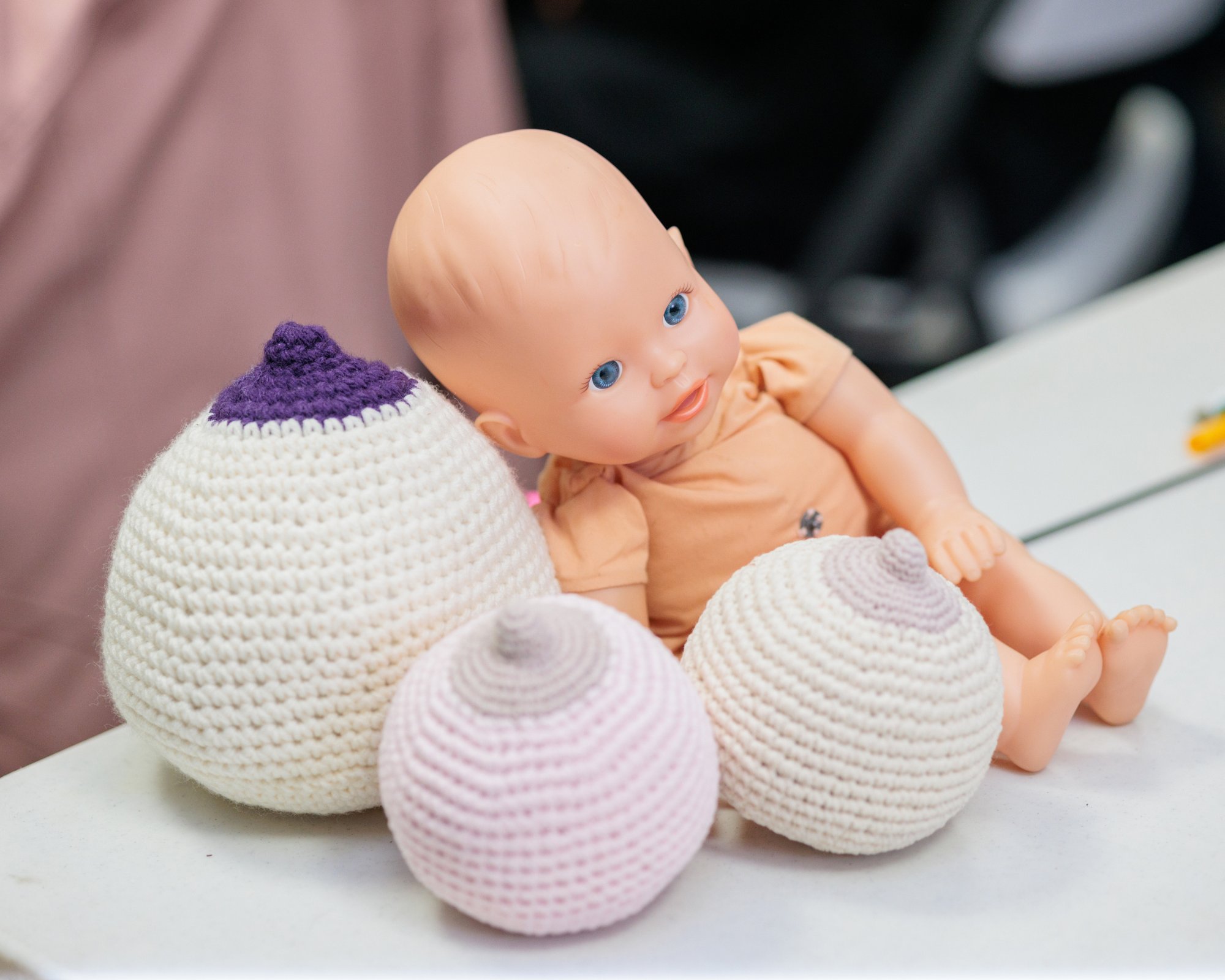 A crocheted breast model and a demonstration doll used to teach latch in a prenatal breastfeeding class