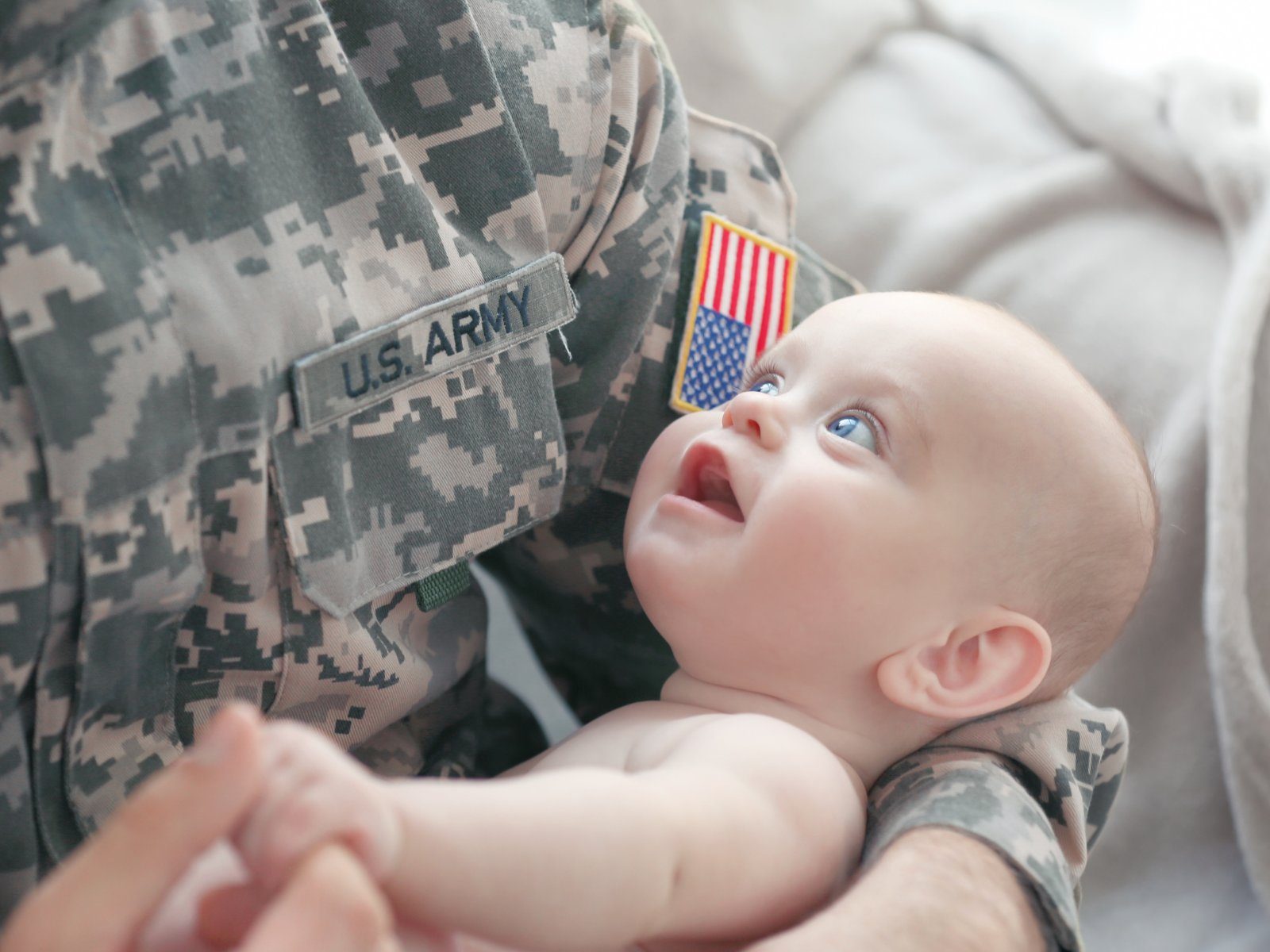 A U.S. Army servicemember in uniform holding their smiling baby