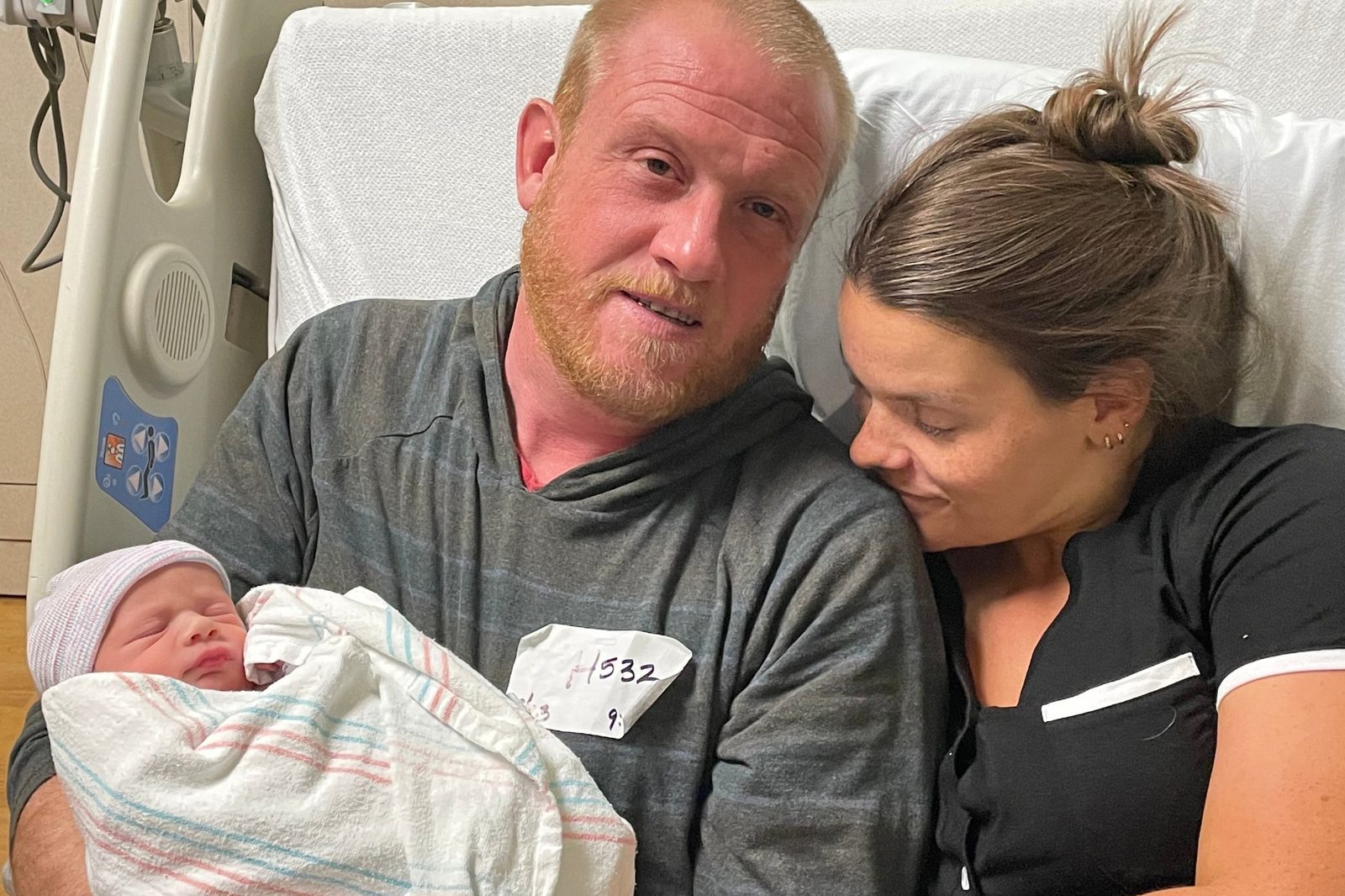 Two parents holding and admiring their newborn baby in the hospital shortly after birth.
