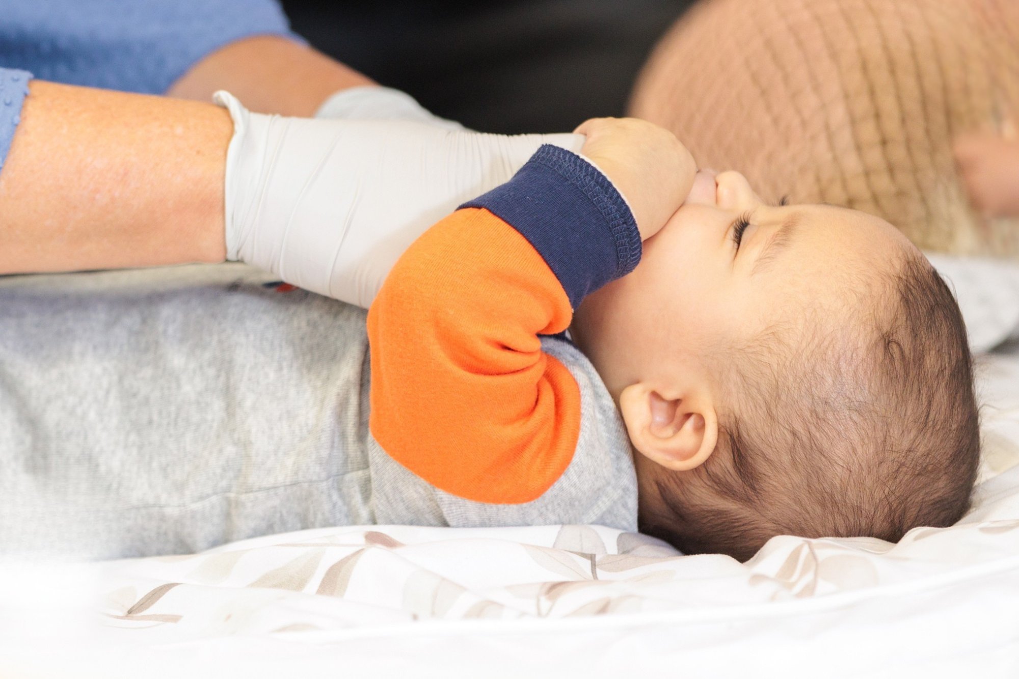 An infant having their tongue and mouth gently examined during an oral function assessment