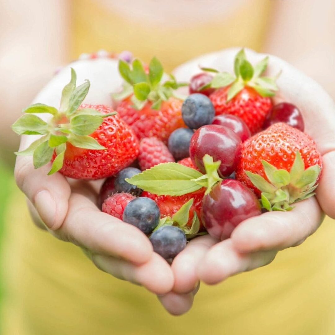 A woman is holding a bunch of berries in her hands.