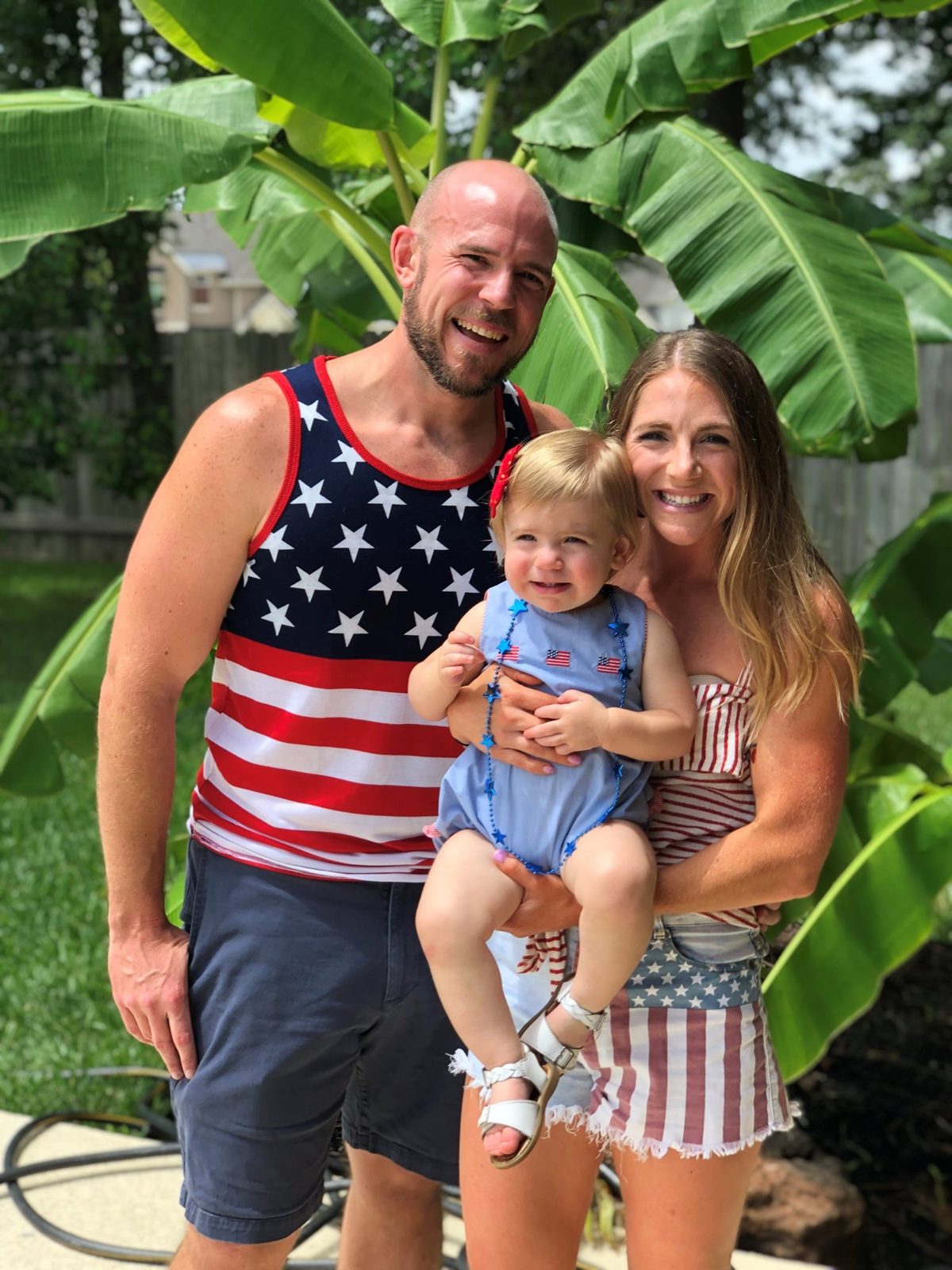 A family in patriotic outfits posing together outdoors.