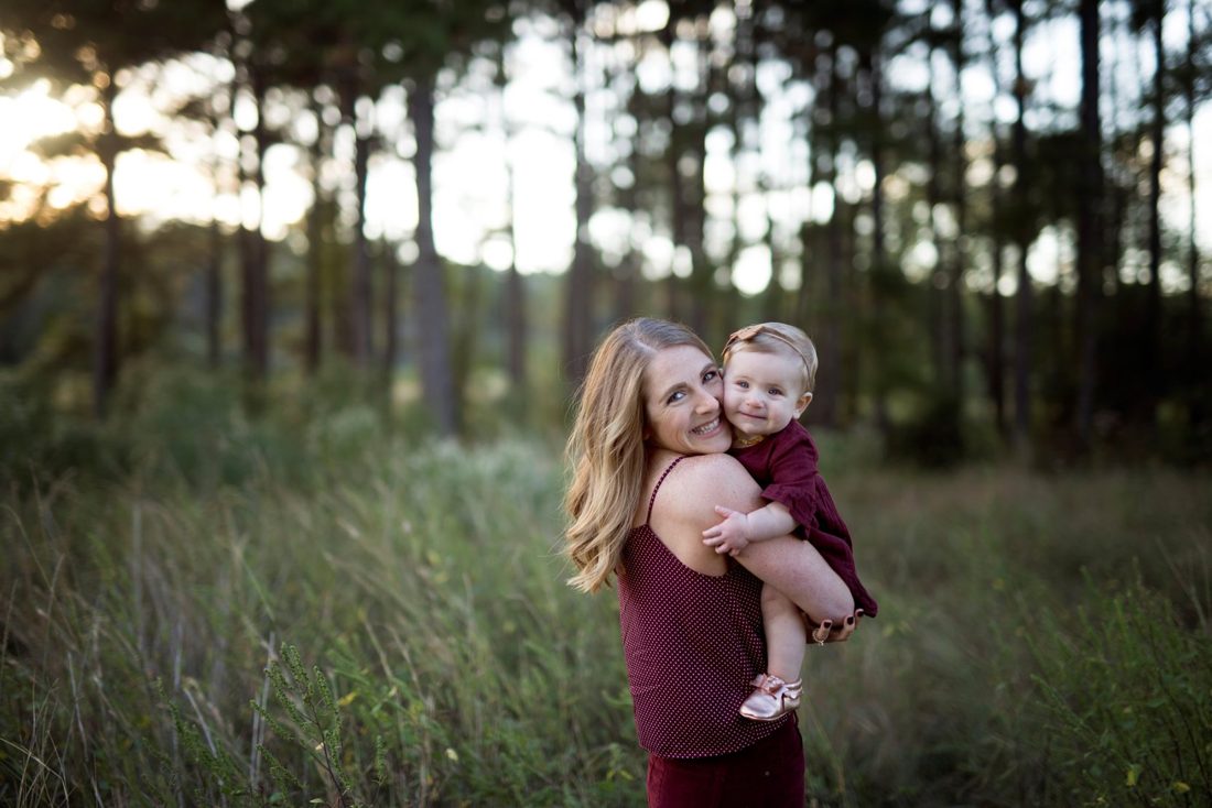 A family standing together in a wooded field at dusk.