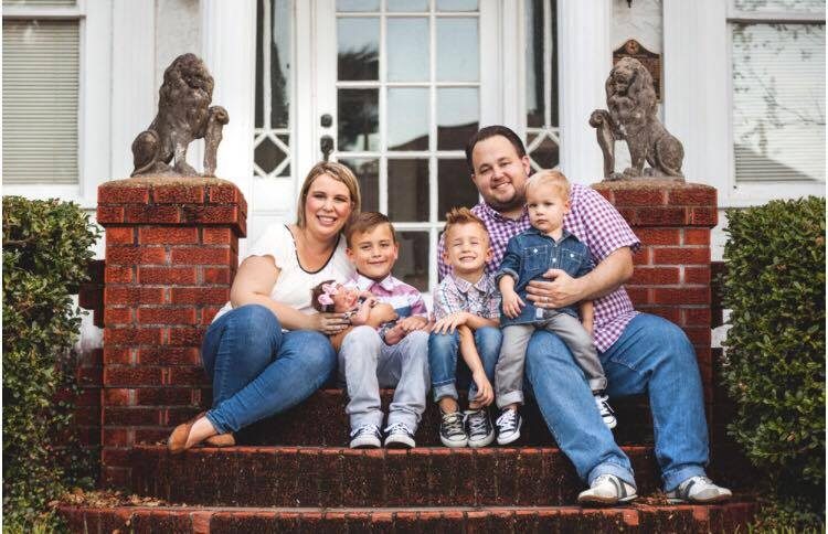 A family of five sitting together on a couch.