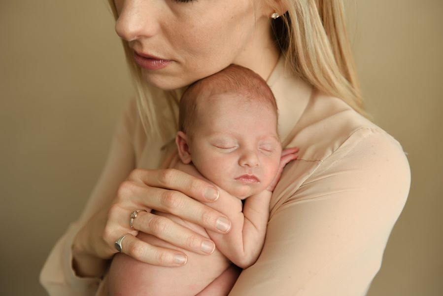 A mother cradling her newborn against her chest.