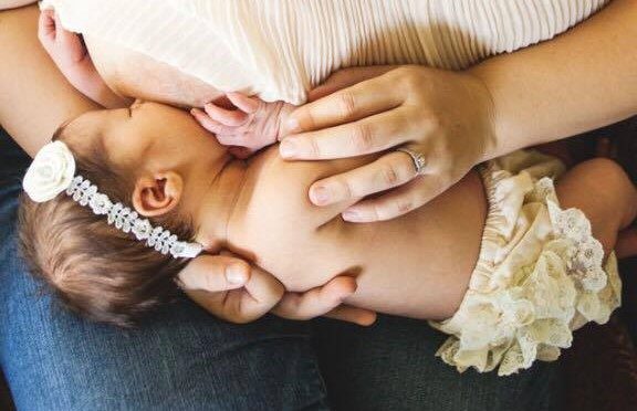 A newborn cradled gently in a parent's hands.