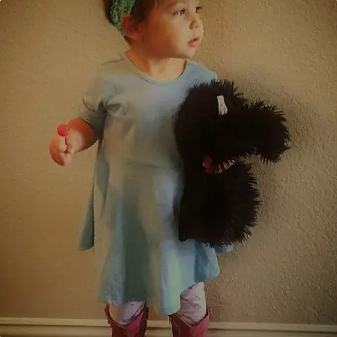 A toddler holding a large stuffed animal outdoors.