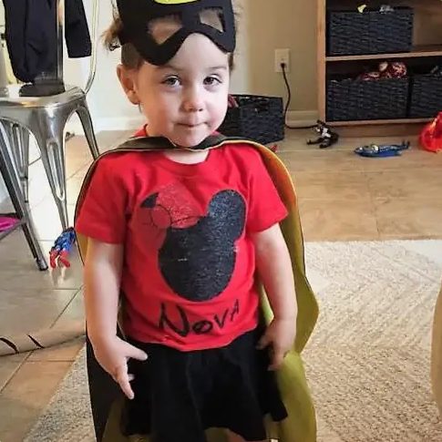A toddler dressed in a superhero costume.