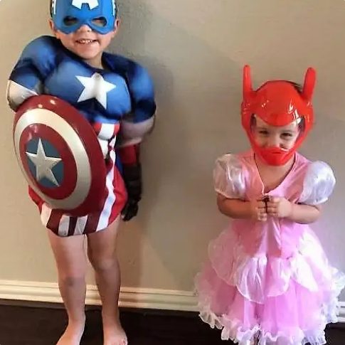 Two toddlers in costumes sitting together on a step.