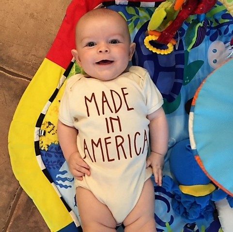 A baby in a patriotic onesie sitting up.