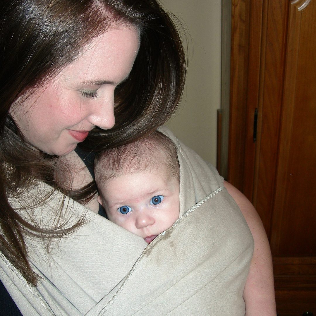 A mother kissing her baby who wears a red headband.