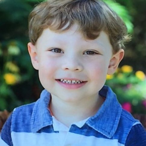 A smiling toddler boy in a striped shirt.