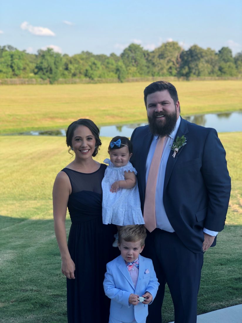 A family of four dressed up in a grassy field.