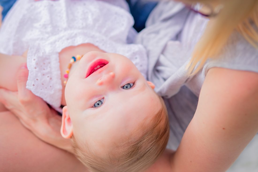 A mother resting her baby across her lap outdoors.