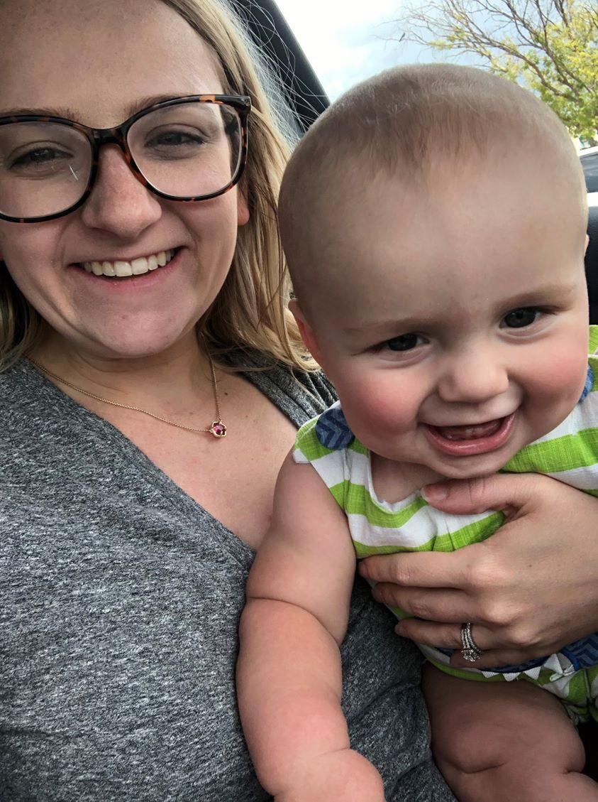 A mother holding her smiling toddler close beside her.
