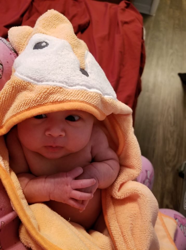 A newborn wrapped in a hooded towel after a bath.
