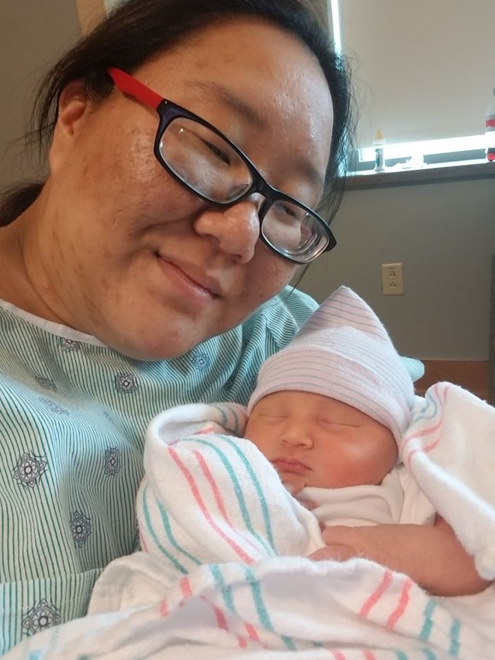 A parent holding a swaddled newborn in the hospital.