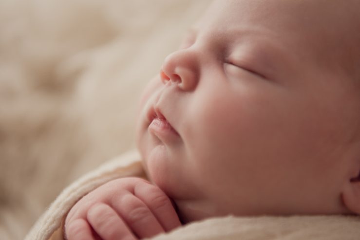 A sleeping newborn photographed in soft close-up.