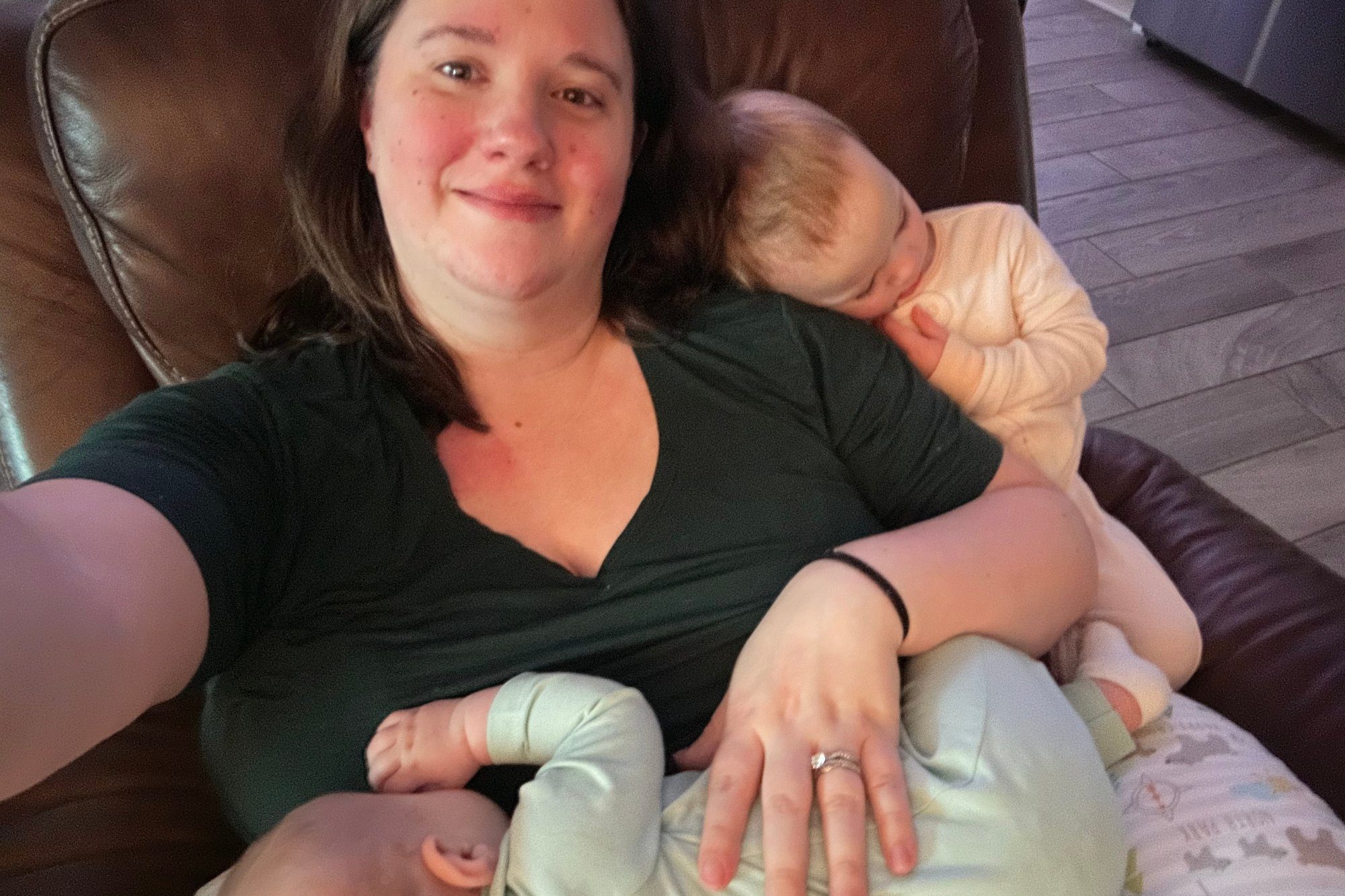 A smiling parent nursing their baby while relaxing in a recliner at home
