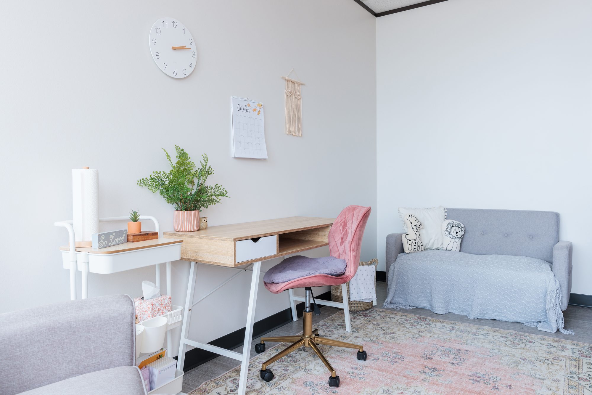A pink velvet office chair at a wooden desk below a wall calendar